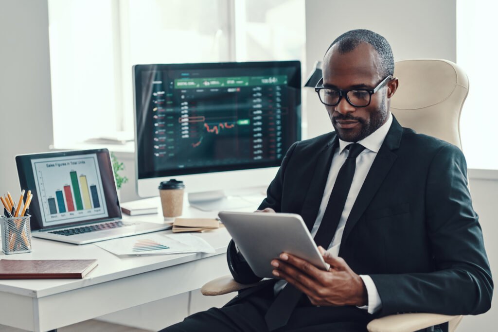 concentrated young african man in formalwear using modern technologies while working in the office